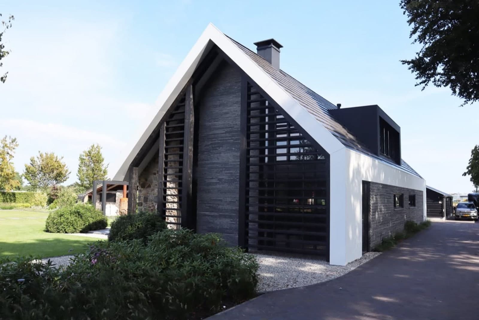 Dezelfde kopgevel na de metamorfose, met natuursteen, hout en een witte dakrand