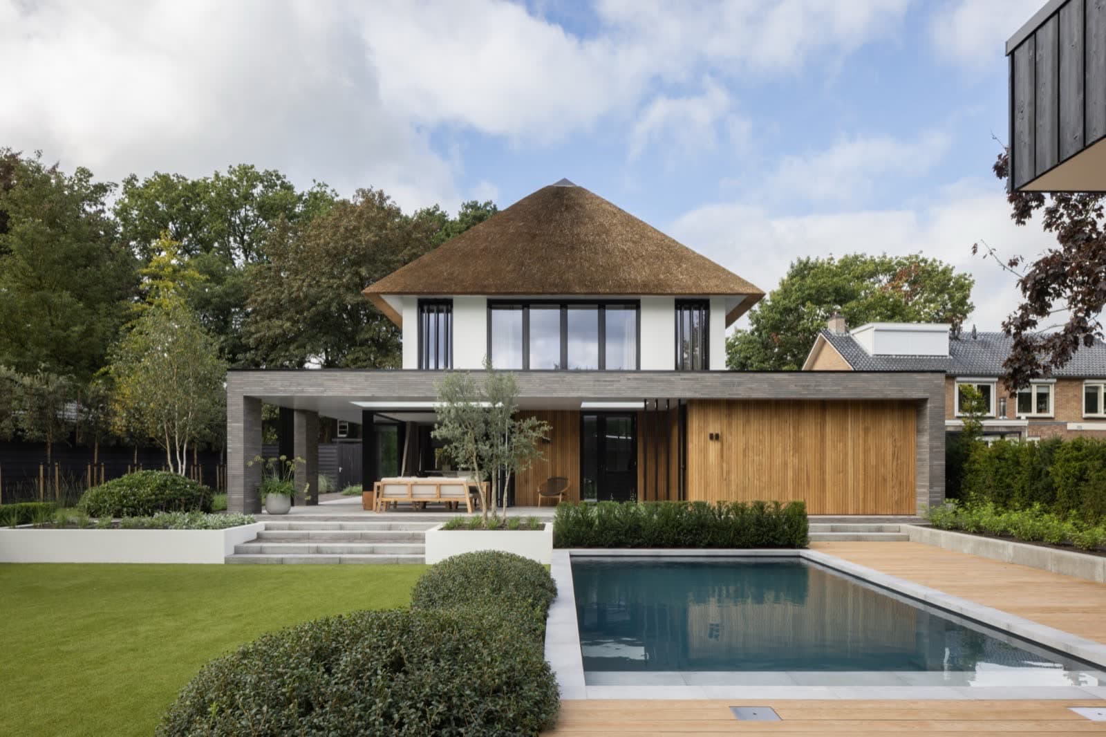 De villa met rieten kap en wit stucwerk, gezien vanaf de tuinzijde