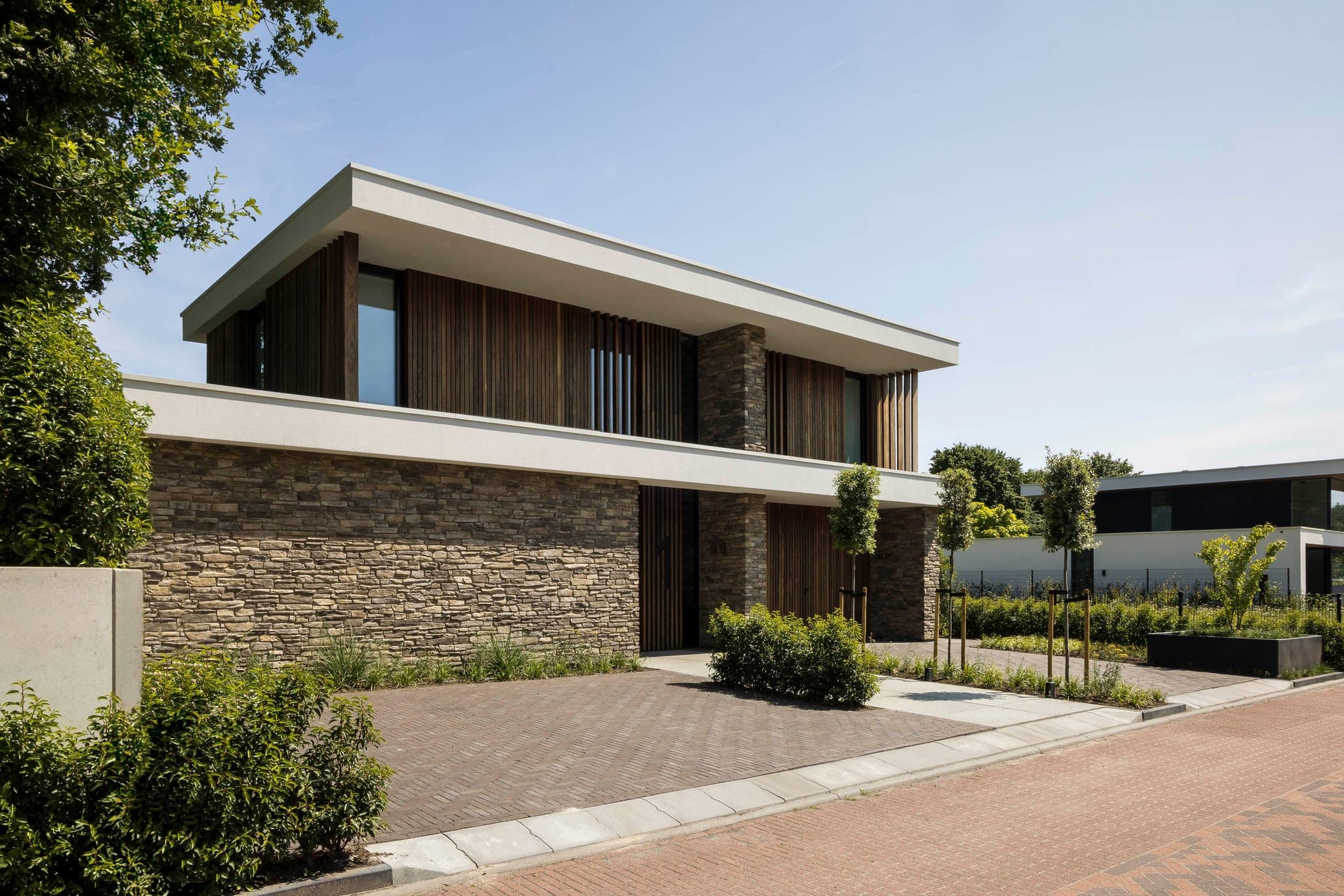 Villa J_01: natuursteen en donker hout onder een witte dakrand