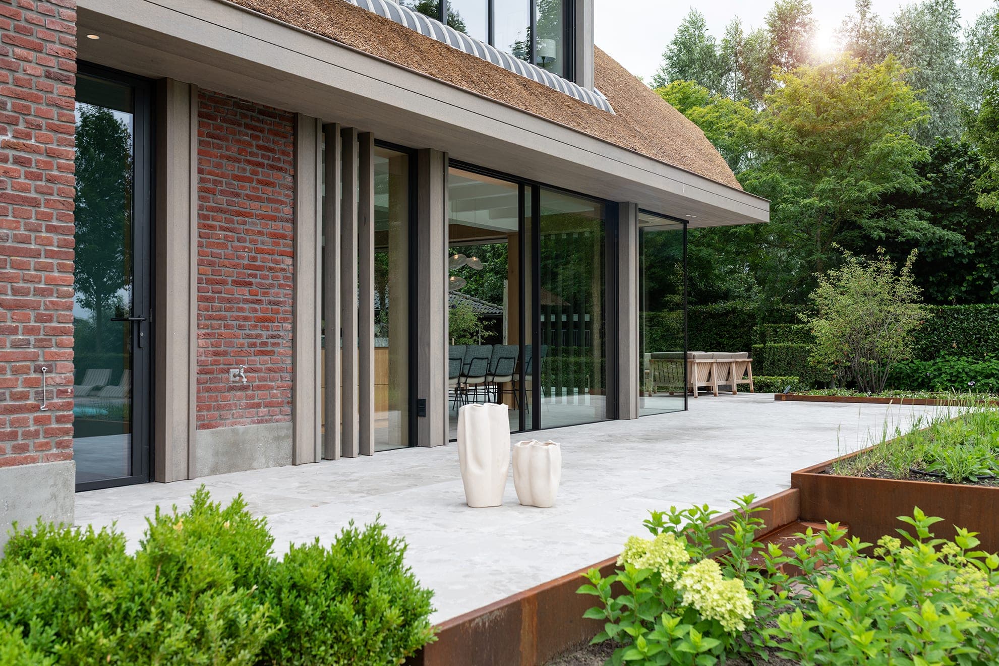 Landhuis R: het terras onder de luifel, met lamellen langs de glazen pui